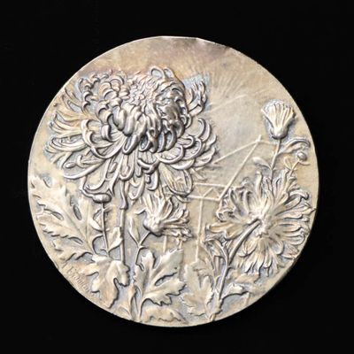 une assiette en argent avec l'image d'une fleur dessus