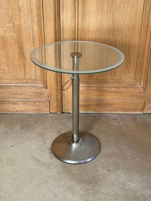 une table en verre avec une base en métal et un plateau en verre