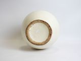 a white vase with a brown rim sitting on a white surface