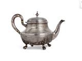 a silver tea pot with a handle on a stand
