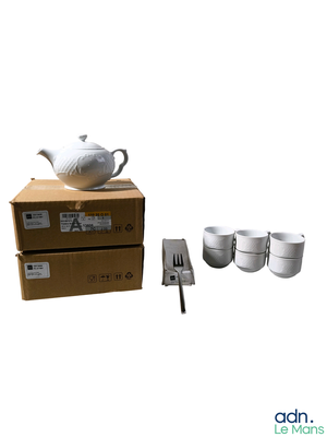 une théière blanche et quatre tasses posées sur une boîte