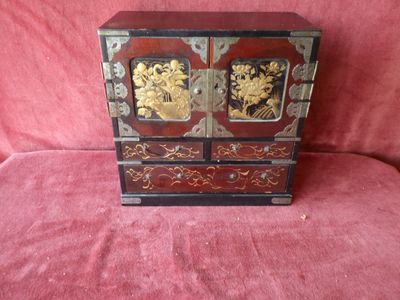 a small wooden cabinet with gold and black decorations on it