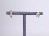 a pair of emerald and diamond earrings on a stand