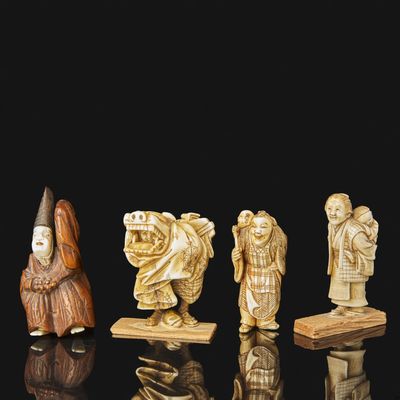 an assortment of carved figurines of people on a black surface