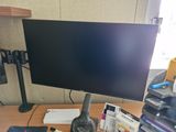 un écran d'ordinateur posé sur un bureau, à côté d'un clavier et d'un casque audio