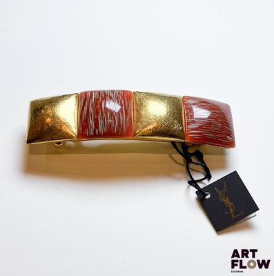 une barrette dorée et rouge, avec une étiquette attachée
