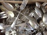a lot of silver spoons and forks in a box