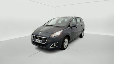 La voiture grise est garée dans une pièce blanche au sol blanc.