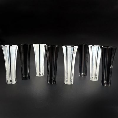 six vases noirs et blancs sont alignés sur une surface noire