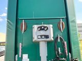 a green portable toilet sitting on the side of the road