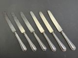 a set of five silverplated knives and a knife on a table