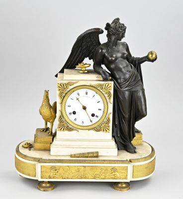 a statue of an angel holding a clock on top of a table