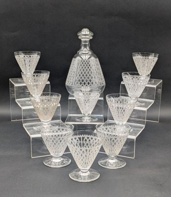 six clear glass wine glasses and a decanter on a clear stand