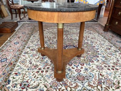 une petite table avec un plateau en marbre posée sur un tapis