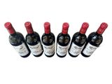 six bottles of wine are lined up in a row on a white surface