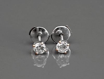 une paire de boucles d'oreilles en diamant posées sur une surface réfléchissante