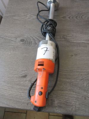 une perceuse électrique orange et blanche posée sur une table en bois