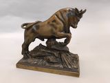 statue en bronze représentant un taureau posé sur un rocher, sur un fond blanc
