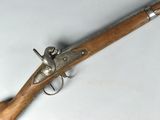 un vieux pistolet avec une poignée en bois sur une surface blanche