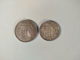 two silver coins sitting side by side on a white surface
