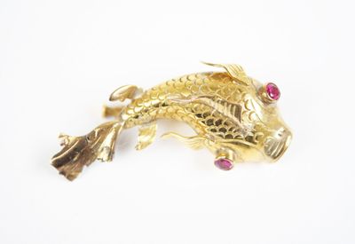 yellow gold fish brooch with ruby eyes on a white background