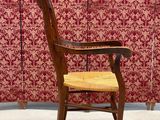 a wooden chair with a wooden seat in front of a red wall