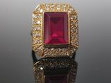 a close up of a ruby and diamond ring on a black surface