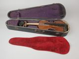 un violon dans son étui, à côté d'une chaussure rouge