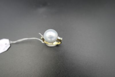 une bague en or sertie d'une perle blanche sur un fond noir