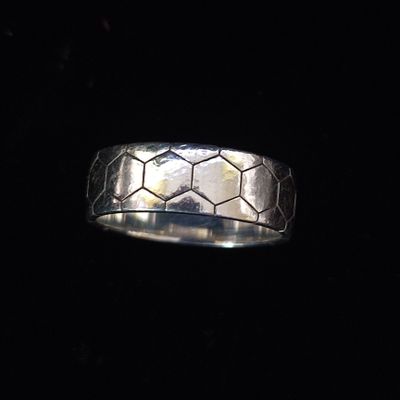 gros plan d'une bague en argent sur une surface noire