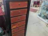 a tall black and red chest of drawers in a store