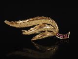 une broche en feuille d'or ornée de pierres roses sur un fond noir