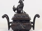 a bronze teapot with a bird on top of it