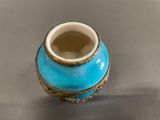 a blue vase sitting on a table with a silver surface