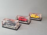 three toy cars are in a clear display case on a gray surface