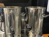 two coffee urns sitting on top of a metal table