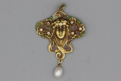 un gros plan d'un pendentif représentant un visage et une perle