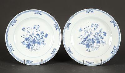 two blue and white plates with flowers on them sitting on a table