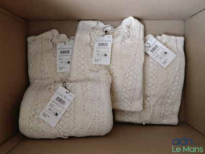 trois sacs de pulls dans une boîte, avec leurs étiquettes de prix