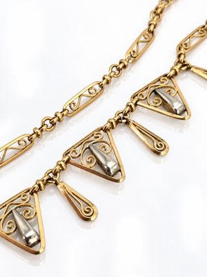 a close up of a gold necklace with a triangle design on it