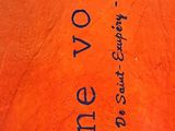 an orange vase with writing on it sitting on the floor