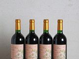 quatre bouteilles de vin posées sur une table en bois, à côté d'une bouteille de vin