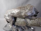 a statue of a frog that is sitting on a piece of wood