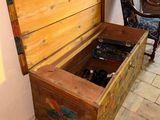 a wooden chest with a painting on the wall next to a chair