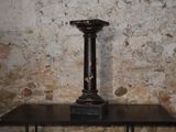 a black table with a candle on it in front of a brick wall