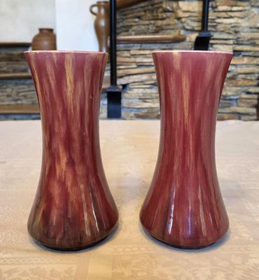 deux vases posés sur une table, avec un mur de pierre en arrière-plan