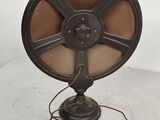 Un ventilateur à l'ancienne est posé sur une table, avec un cordon d'alimentation