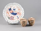 two vases and a plate on display on a table
