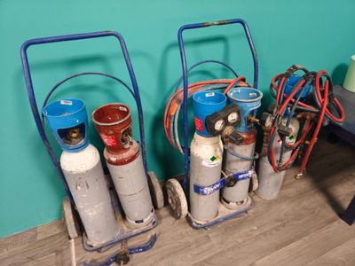 trois bouteilles de gaz propane posées sur un chariot près d'un mur bleu