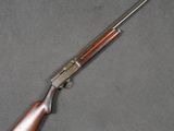 un fusil avec une crosse et un canon en bois, posé sur une surface grise